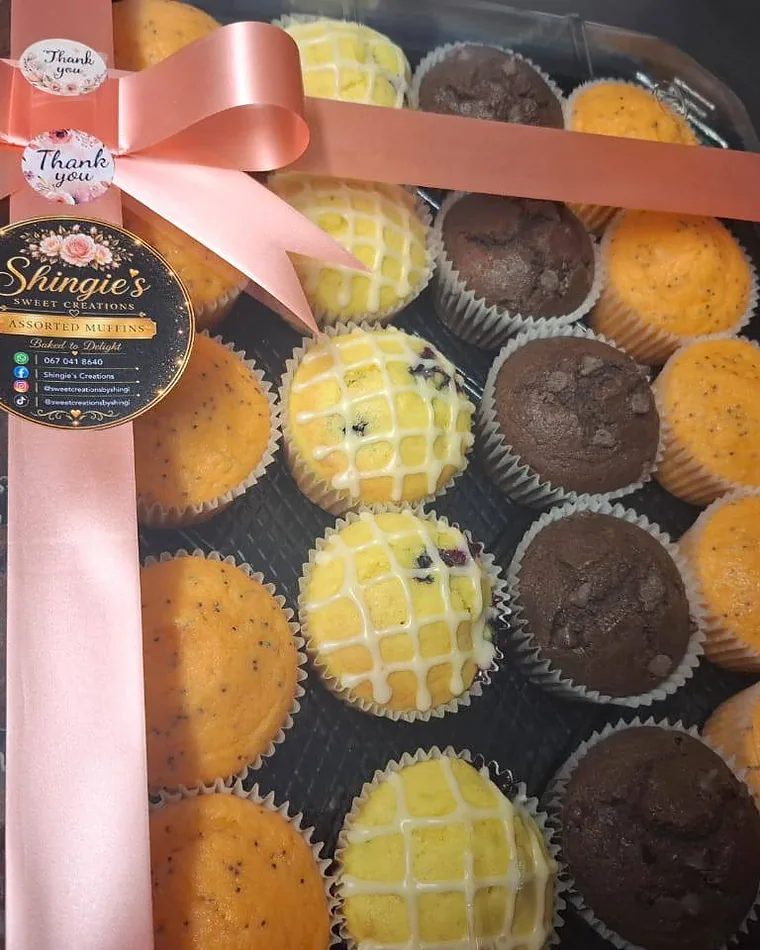 A gift box of assorted muffins tied with a blush ribbon and a Shingie's Sweet Creations seal